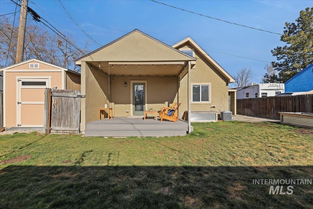Rear view of property with stucco siding, a fenced backyard, a storage shed, and a patio area
