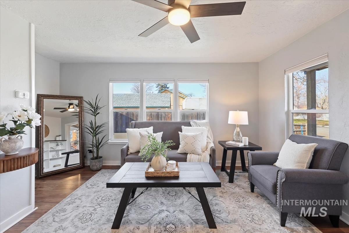 Living area with ceiling fan, wood finished floors, and a textured ceiling