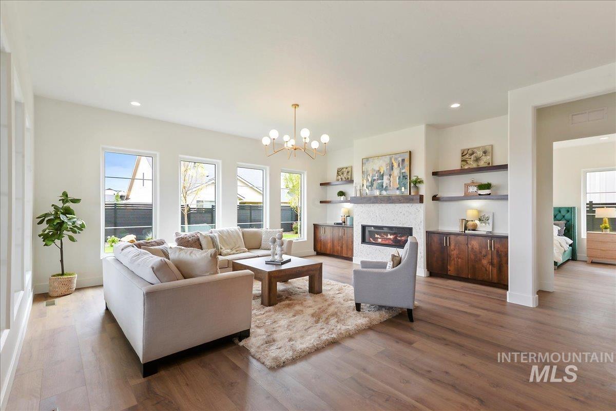 Living area with dark wood-type flooring, a chandelier, a glass covered fireplace, and recessed lighting