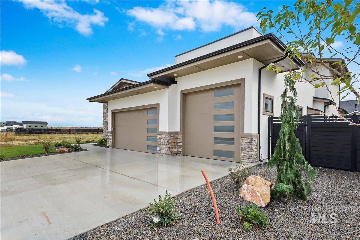 View of side of property featuring stone siding, stucco siding, concrete driveway, and an attached garage