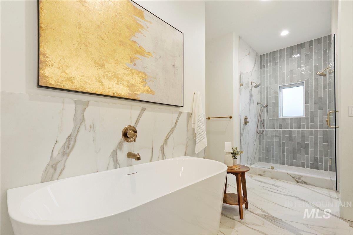 Bathroom with a shower stall, marble tiled flooring, a freestanding tub, and recessed lighting