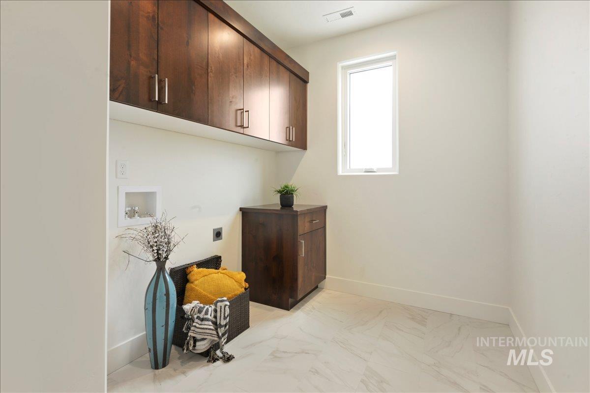 Laundry room featuring cabinet space, hookup for a washing machine, light marble finish flooring, and hookup for an electric dryer