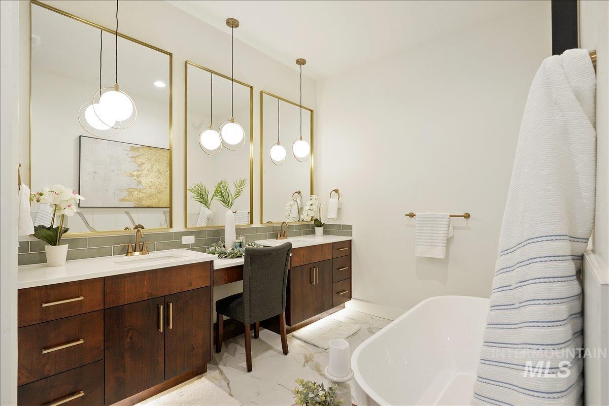 Bathroom featuring a soaking tub, backsplash, vanity, and light marble finish floors