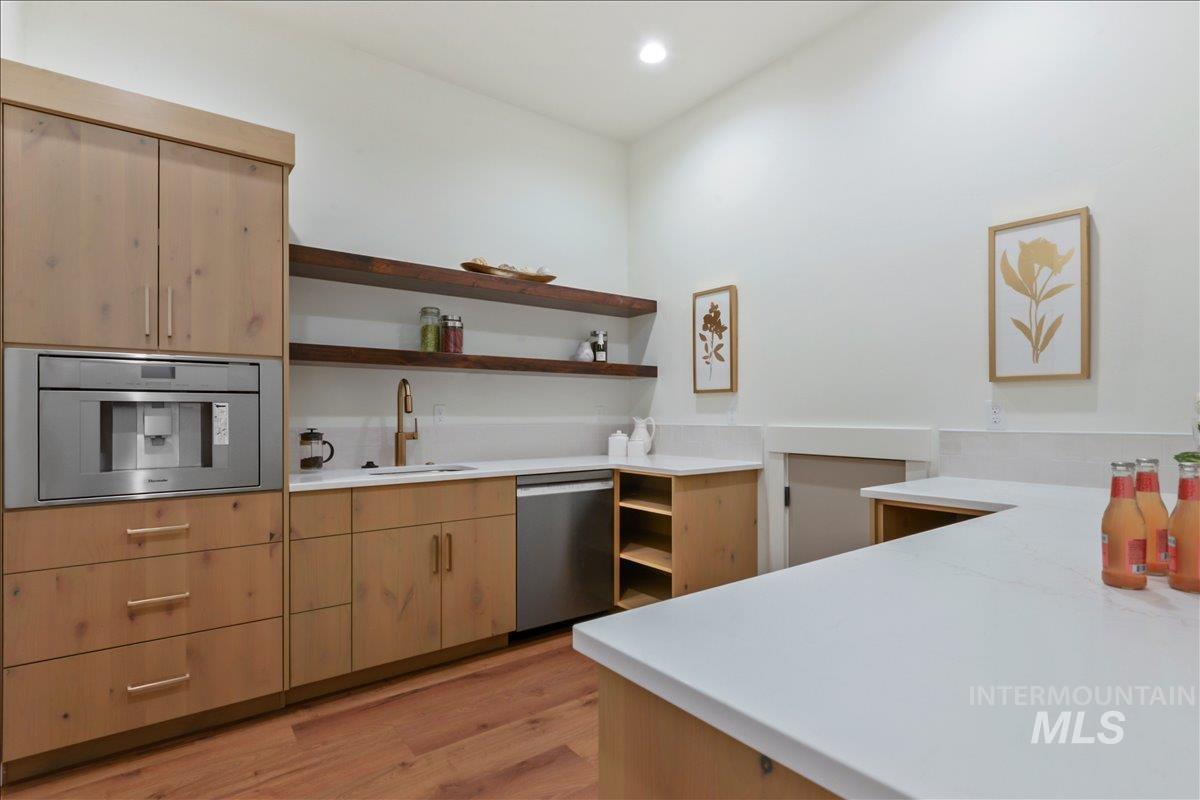 Kitchen featuring open shelves, light brown cabinetry, light wood finished floors, and appliances with stainless steel finishes