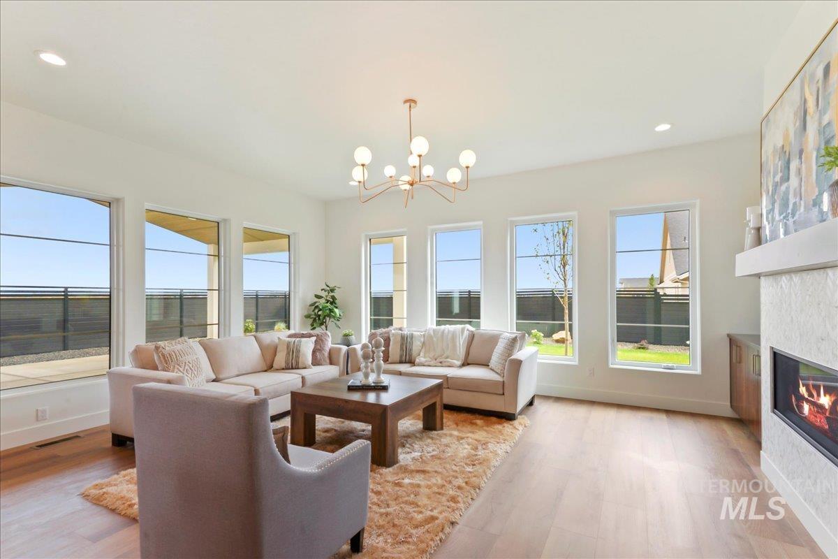 Living area with light wood-style flooring, recessed lighting, a glass covered fireplace, and a chandelier