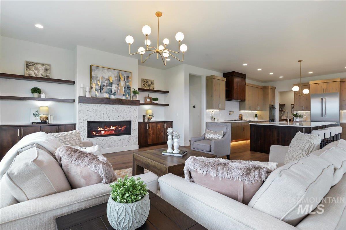 Living area featuring dark wood-style flooring, a glass covered fireplace, recessed lighting, and a chandelier