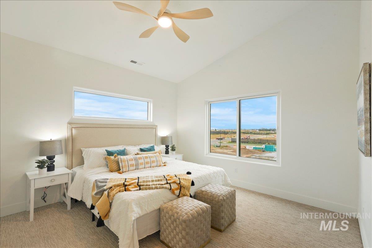 Bedroom with light carpet, high vaulted ceiling, and a ceiling fan