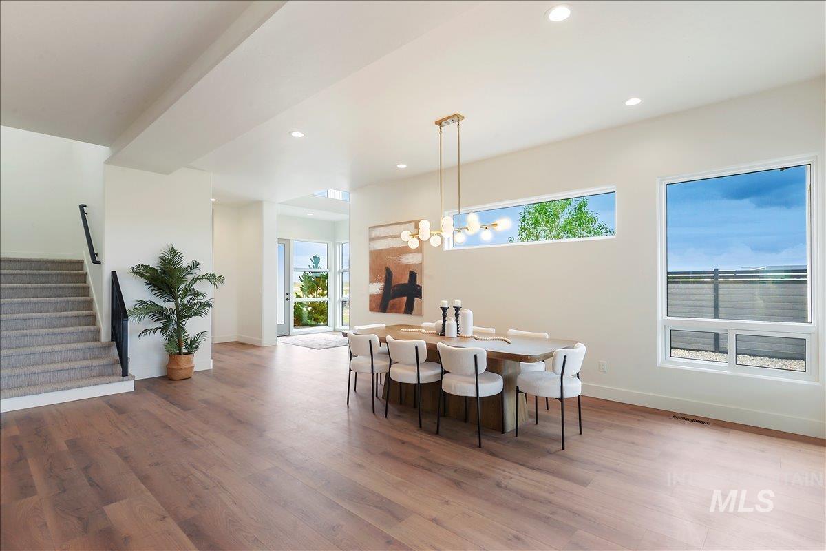 Dining space with wood finished floors, recessed lighting, a chandelier, and stairway