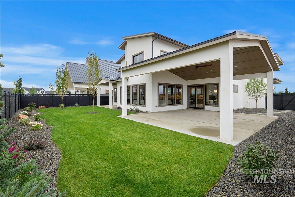 Back of house featuring ceiling fan, a fenced backyard, stucco siding, and a patio area