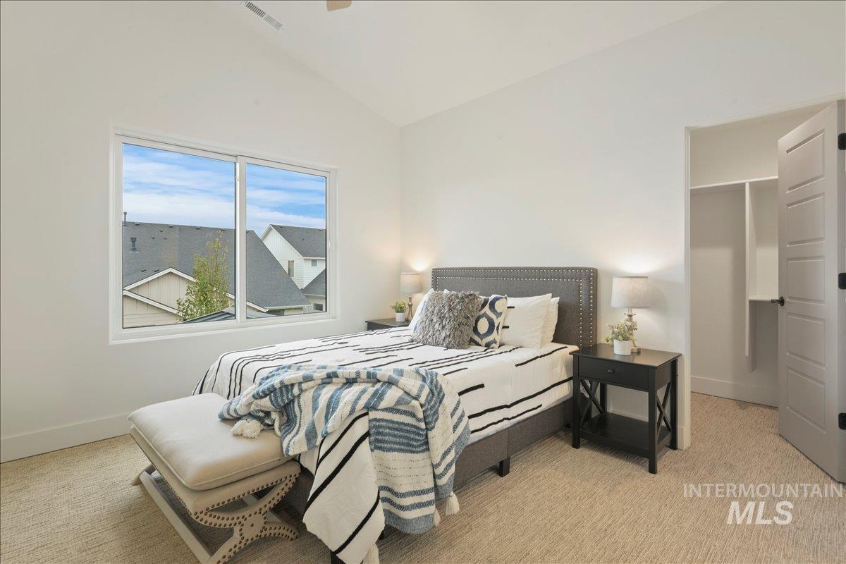 Bedroom with lofted ceiling, light colored carpet, and ceiling fan