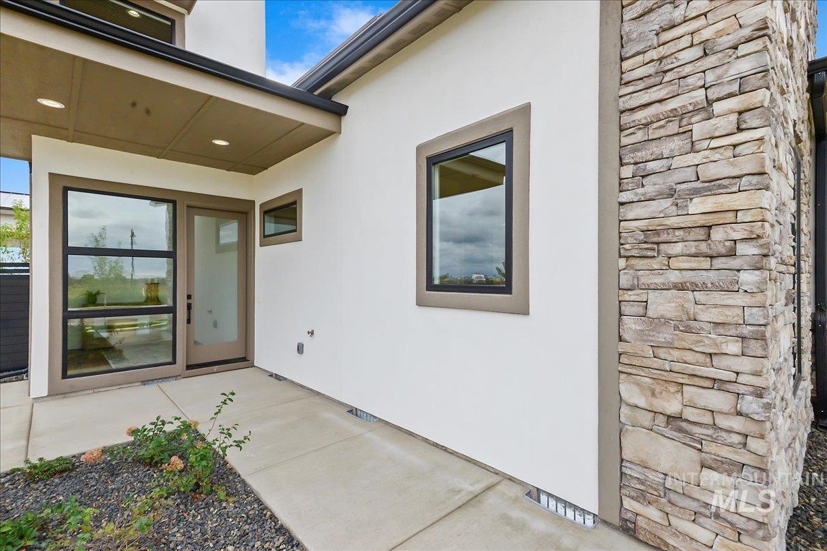 Property entrance with stone siding and stucco siding
