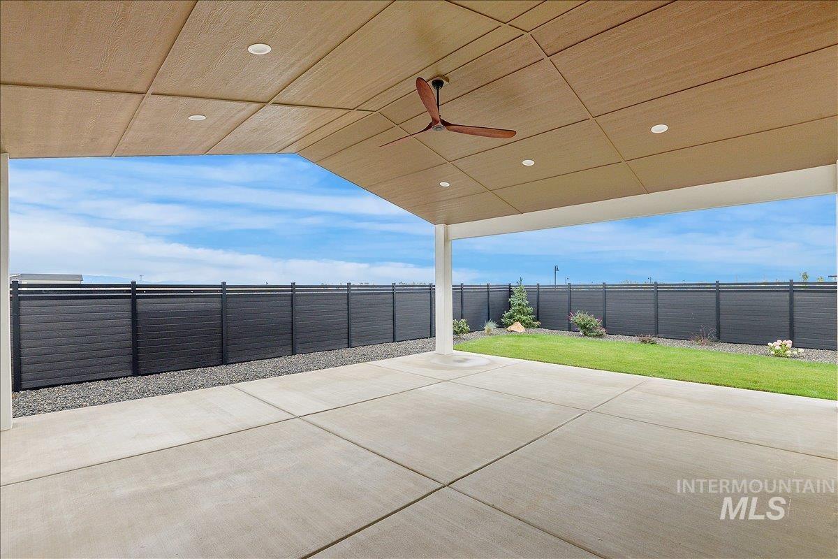 Fenced backyard featuring a ceiling fan and a patio area