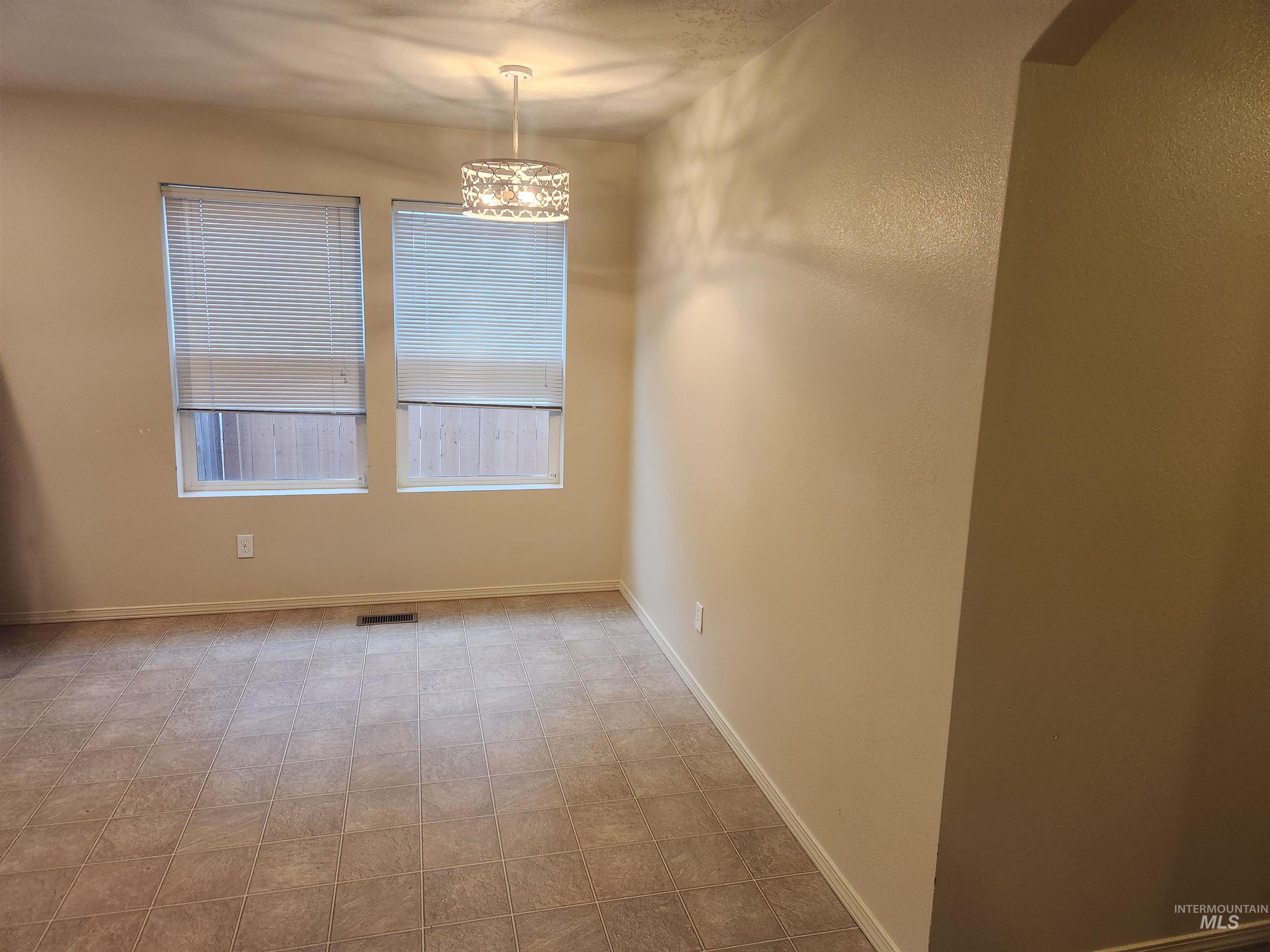 Empty room featuring baseboards and a chandelier