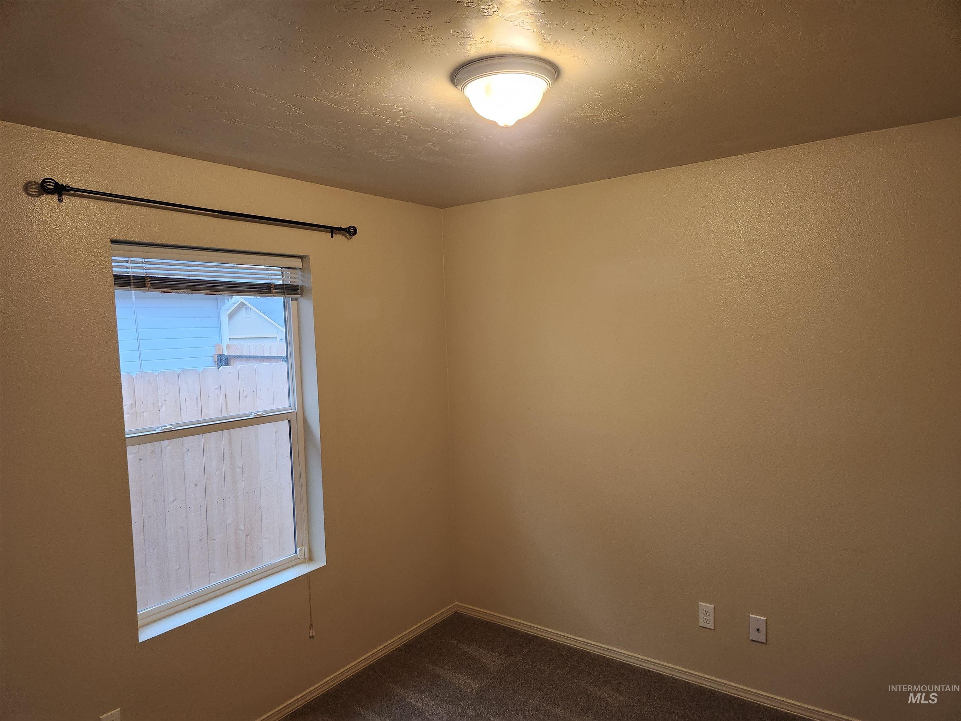 Spare room featuring dark carpet and a textured ceiling