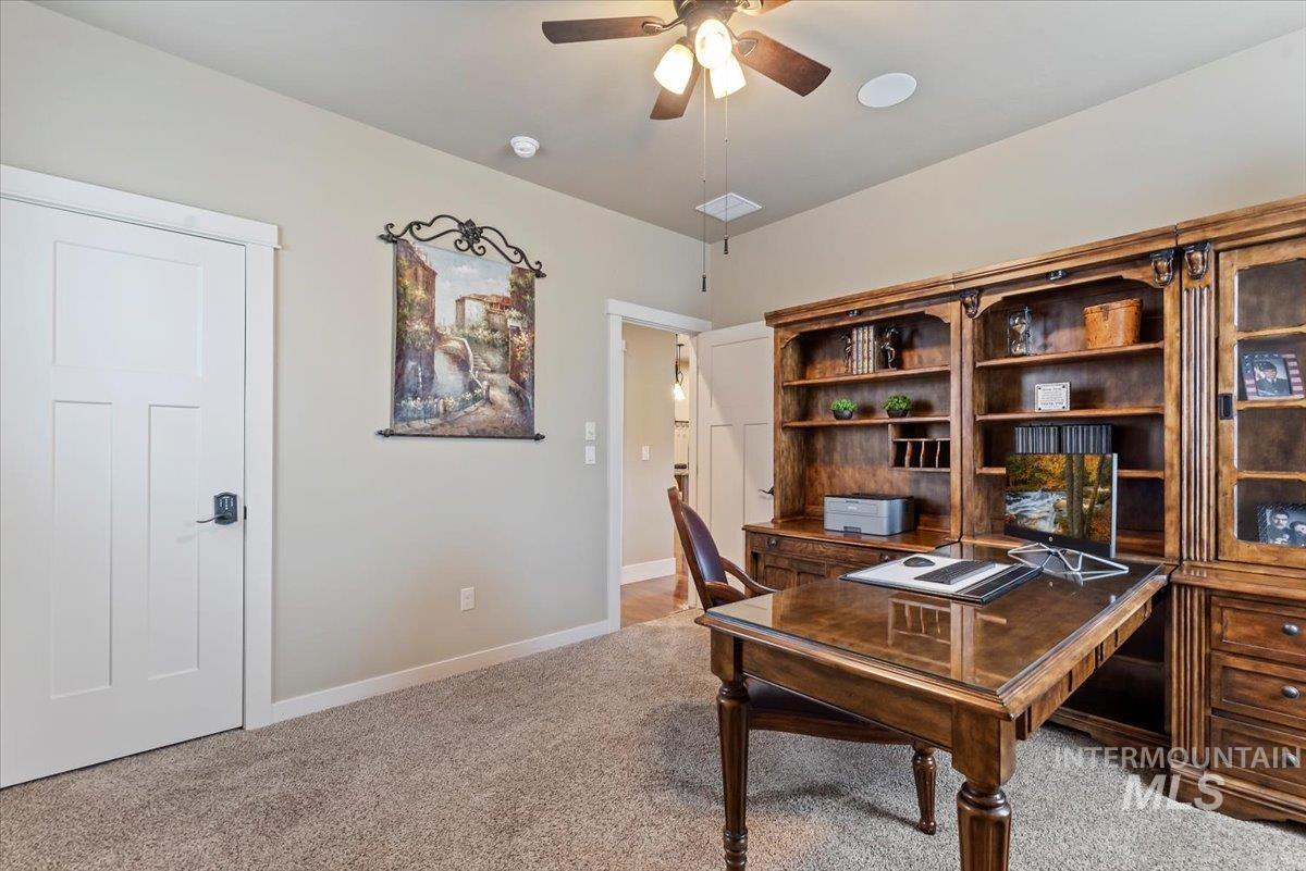 Office area with light colored carpet and a ceiling fan