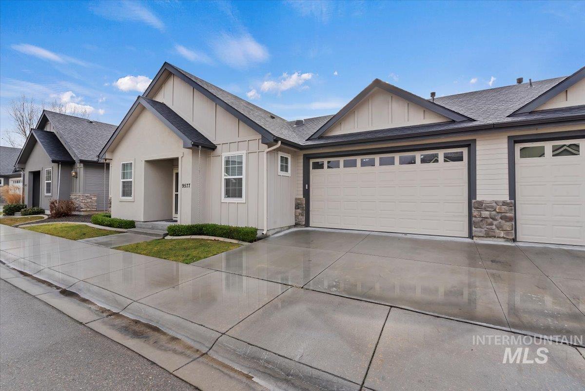 View of front of property with board and batten siding, driveway, roof with shingles, and a garage