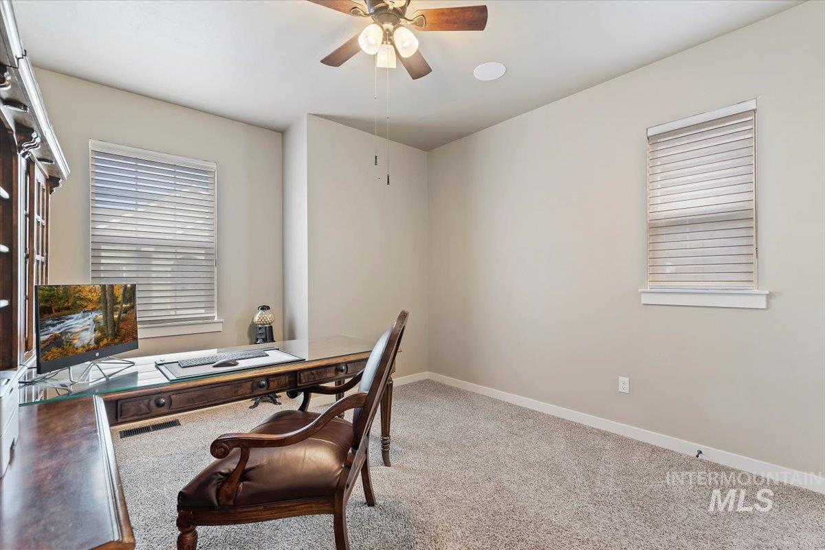Office space with light carpet and ceiling fan