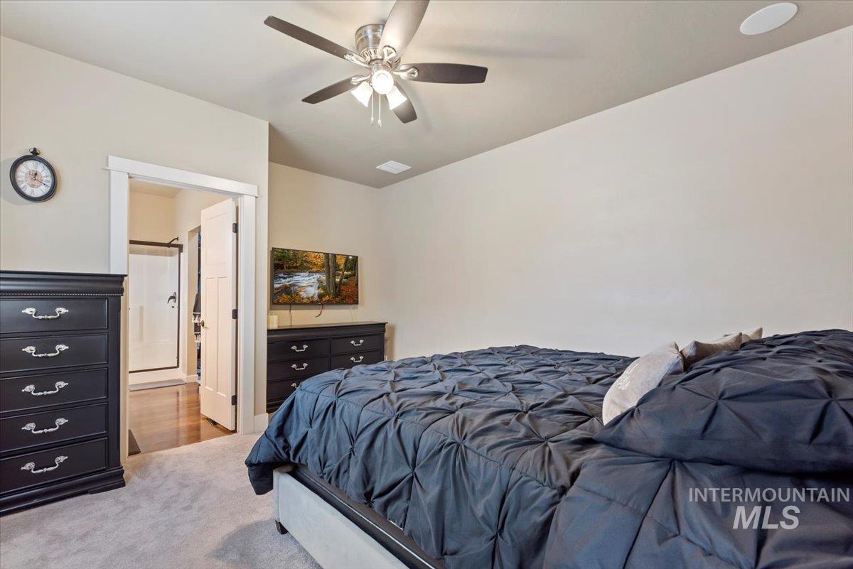 Carpeted bedroom featuring ceiling fan and connected bathroom