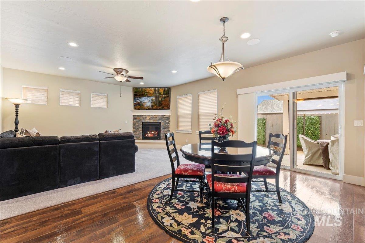 Dining area with wood-type flooring, healthy amount of natural light, a stone fireplace, and recessed lighting
