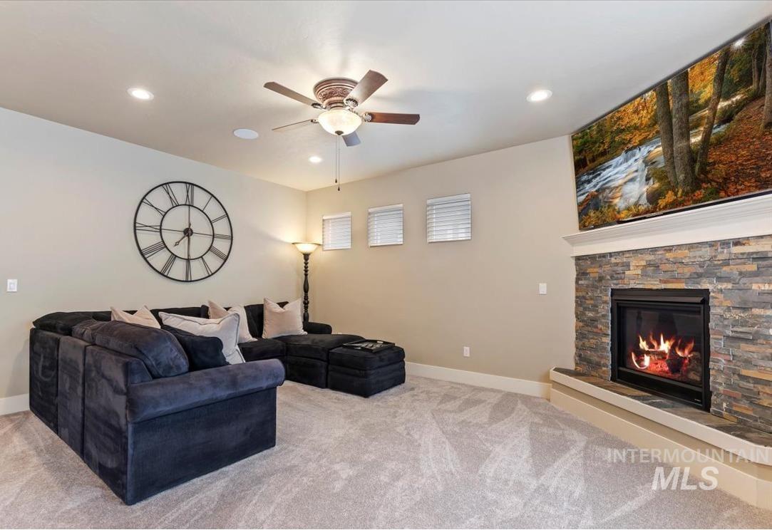 Living room featuring a stone fireplace, light colored carpet, recessed lighting, and a ceiling fan