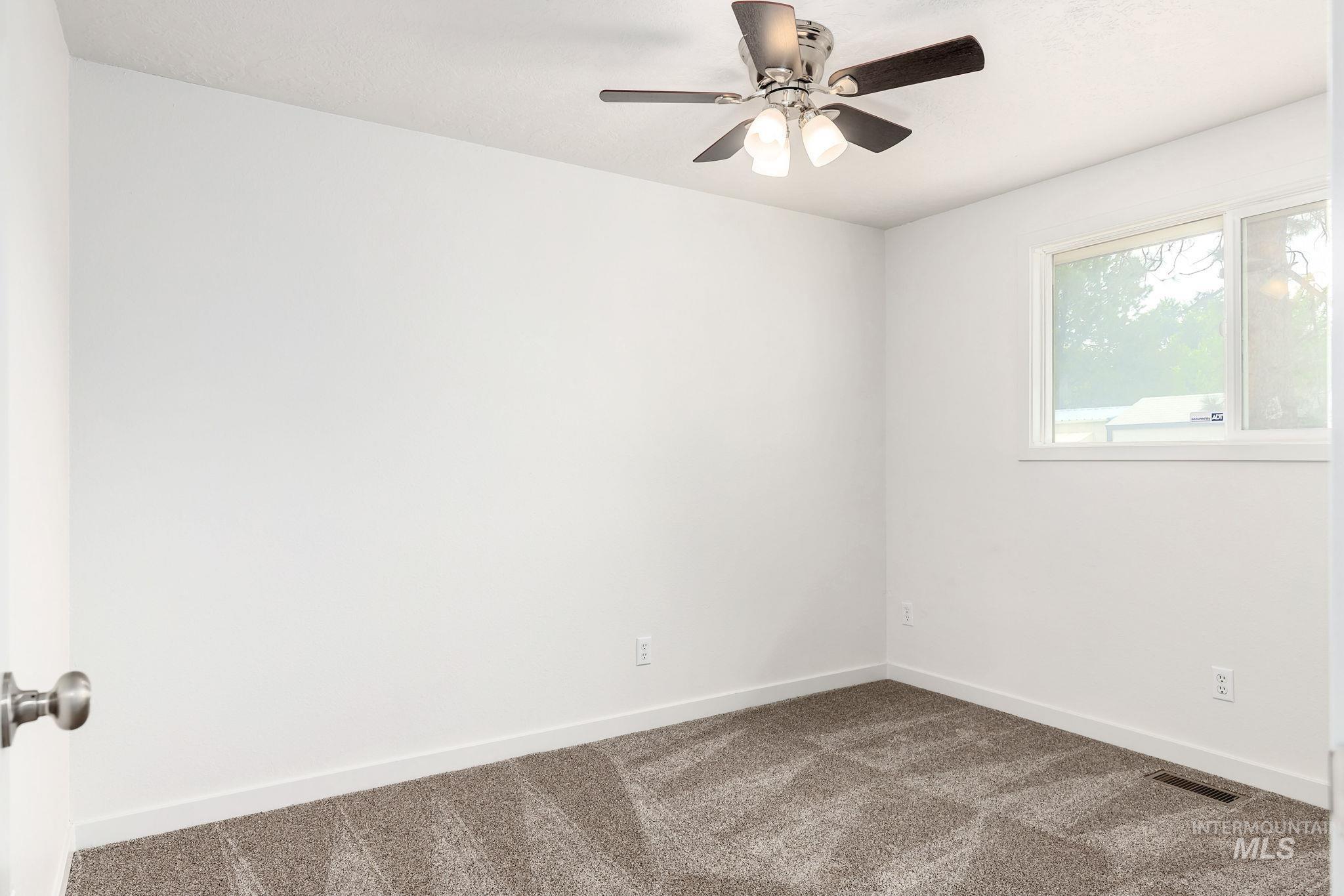 Carpeted spare room with baseboards and a ceiling fan