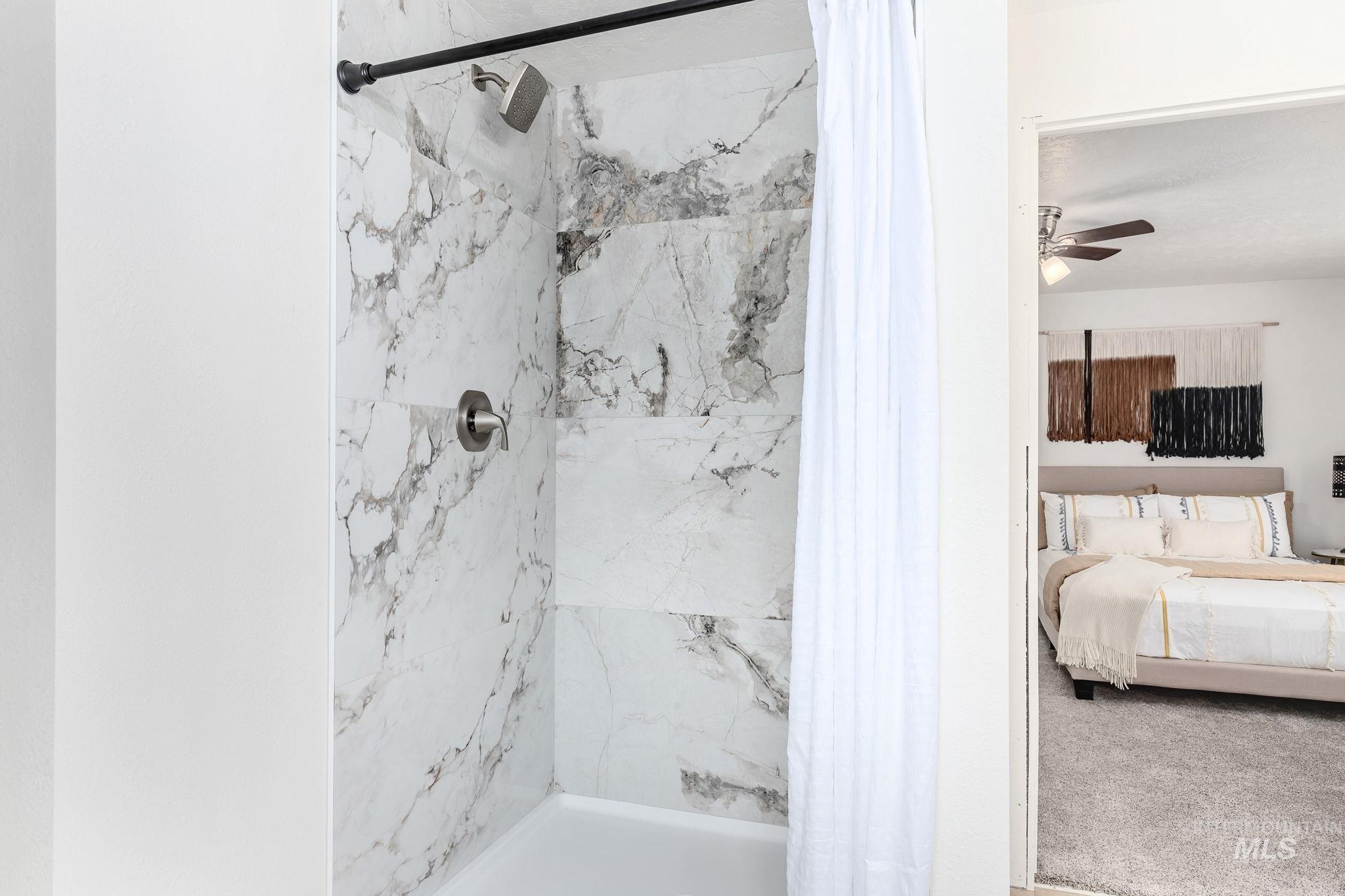 Ensuite bathroom with a tile shower and a ceiling fan