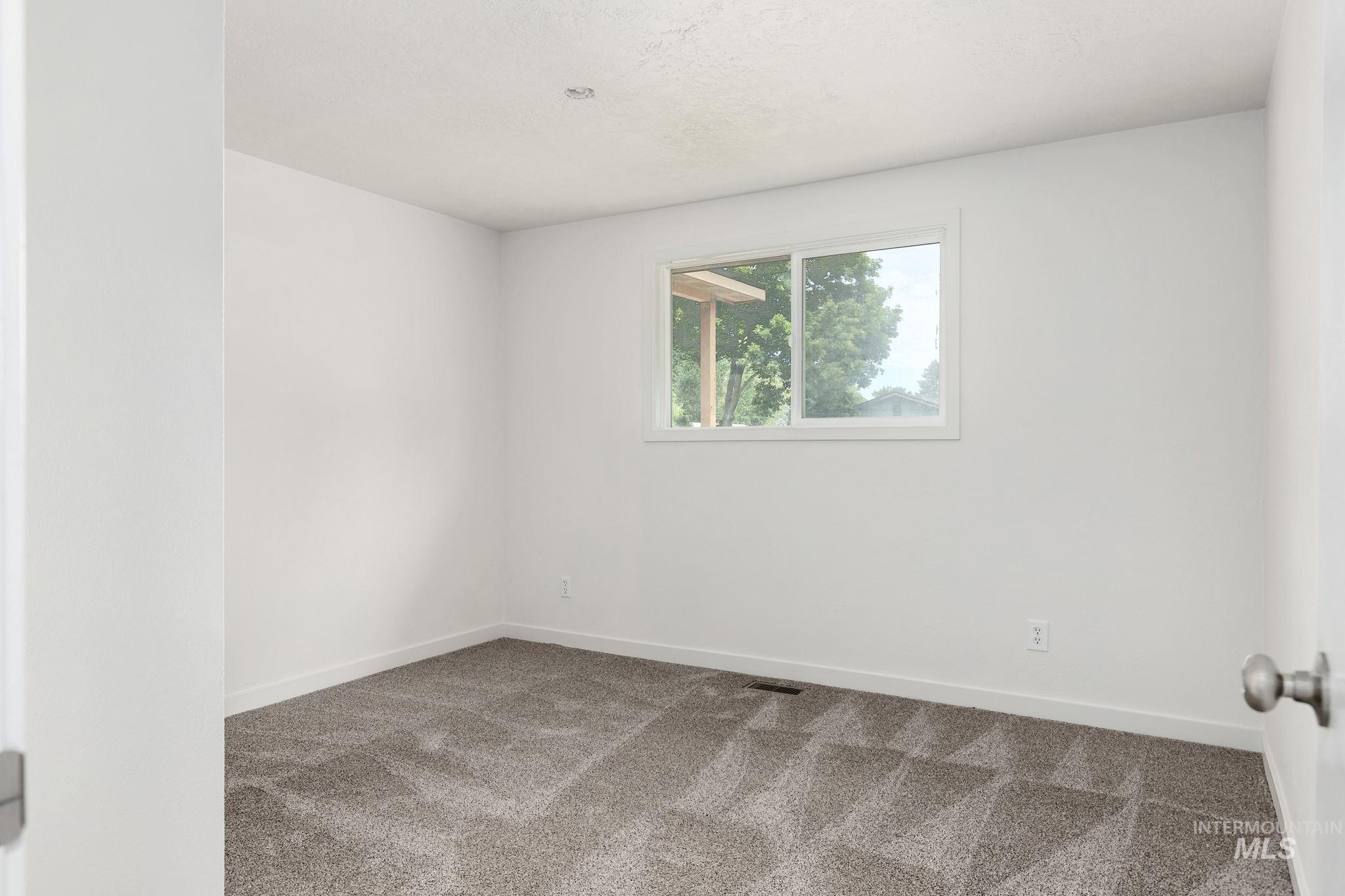 Carpeted spare room featuring baseboards