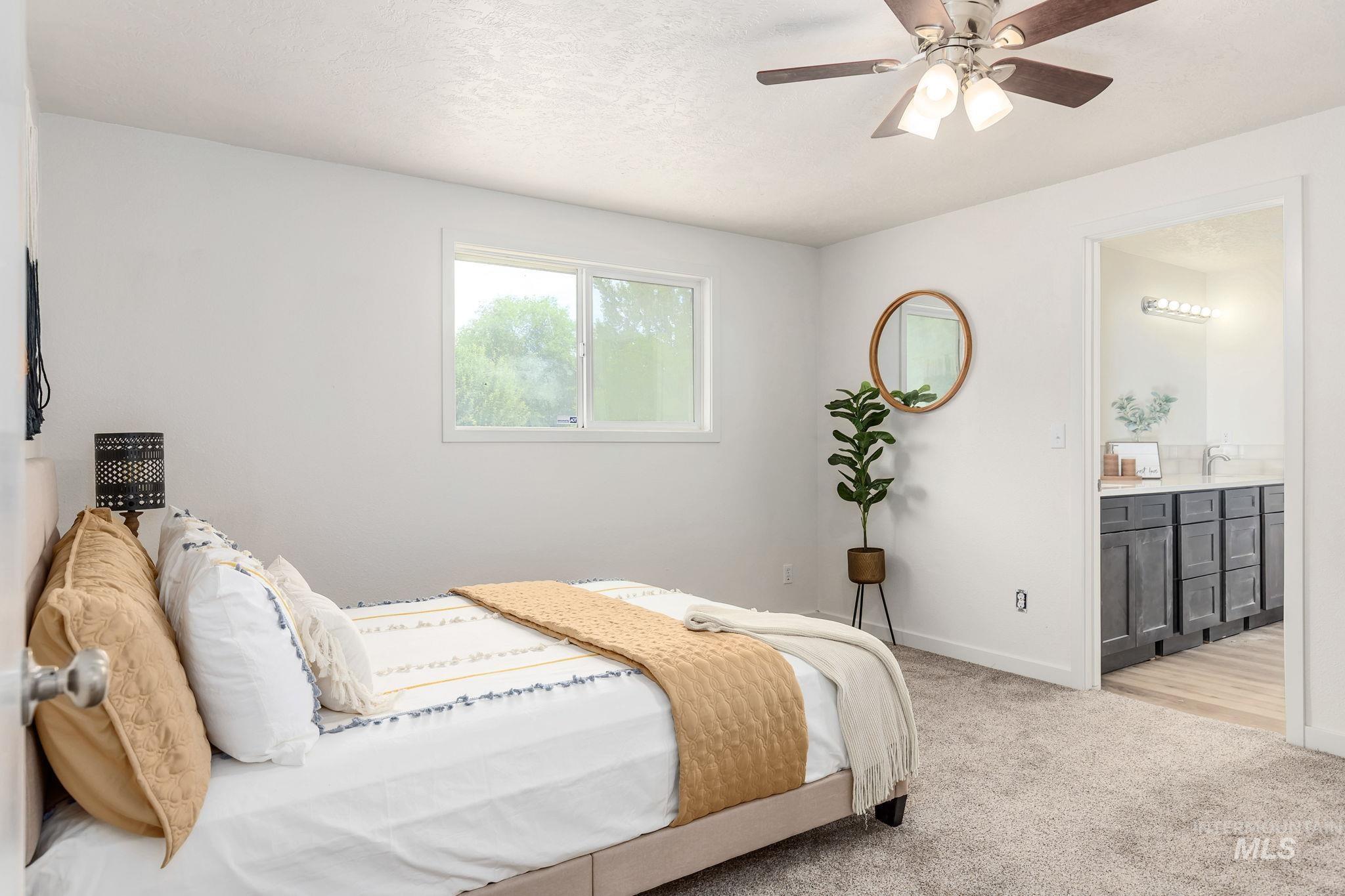 Bedroom with light colored carpet, ensuite bathroom, and a ceiling fan