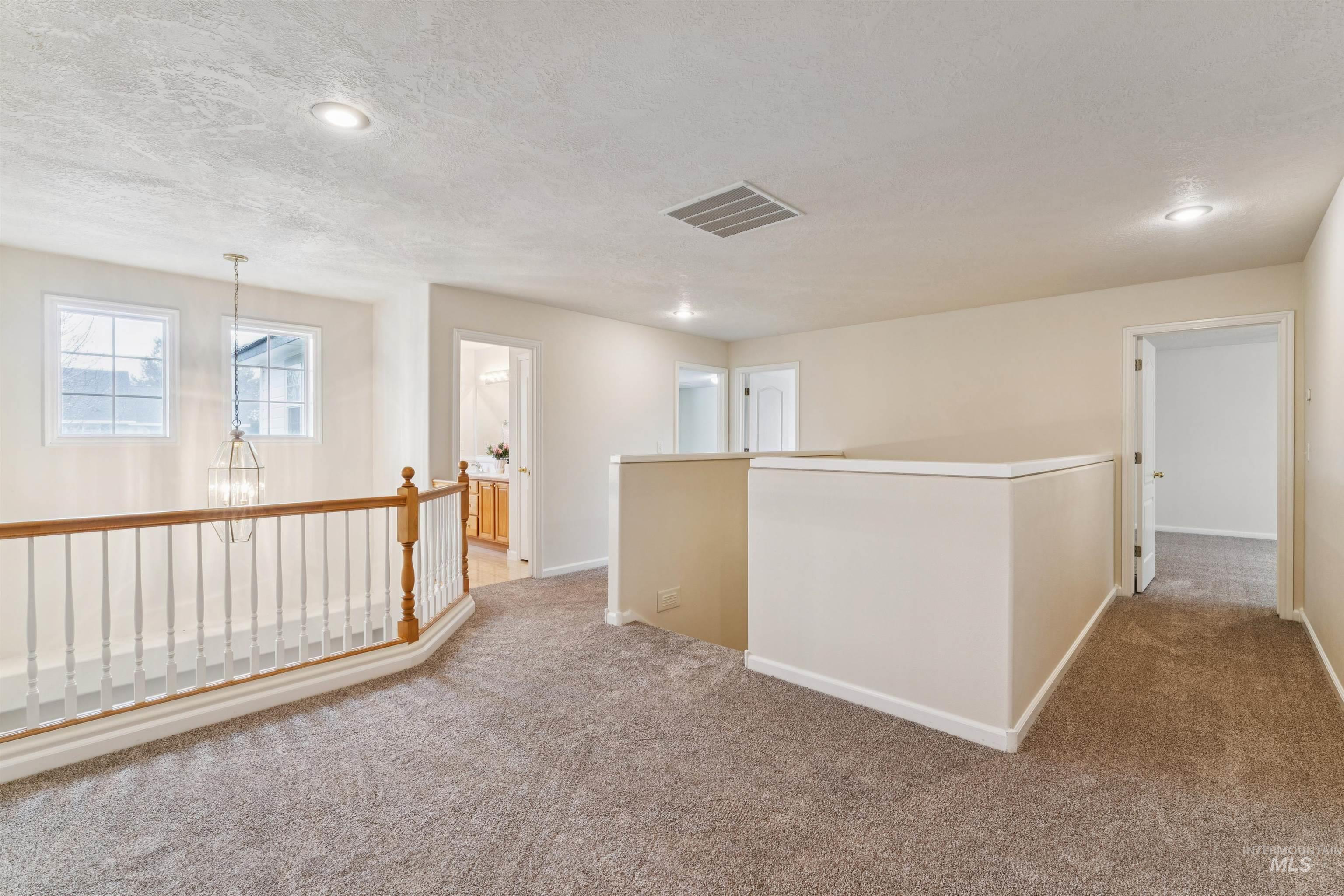 Hallway featuring carpet floors, a textured ceiling, recessed lighting, an upstairs landing, and a chandelier