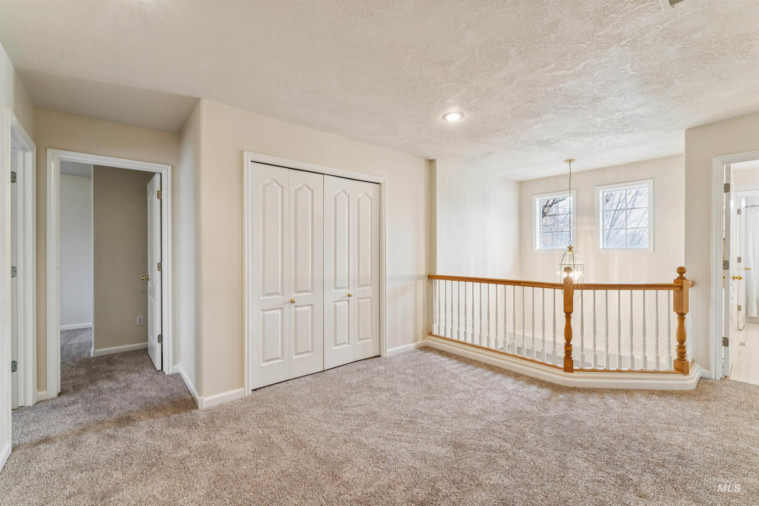 Unfurnished bedroom featuring a closet, carpet floors, a chandelier, and a textured ceiling