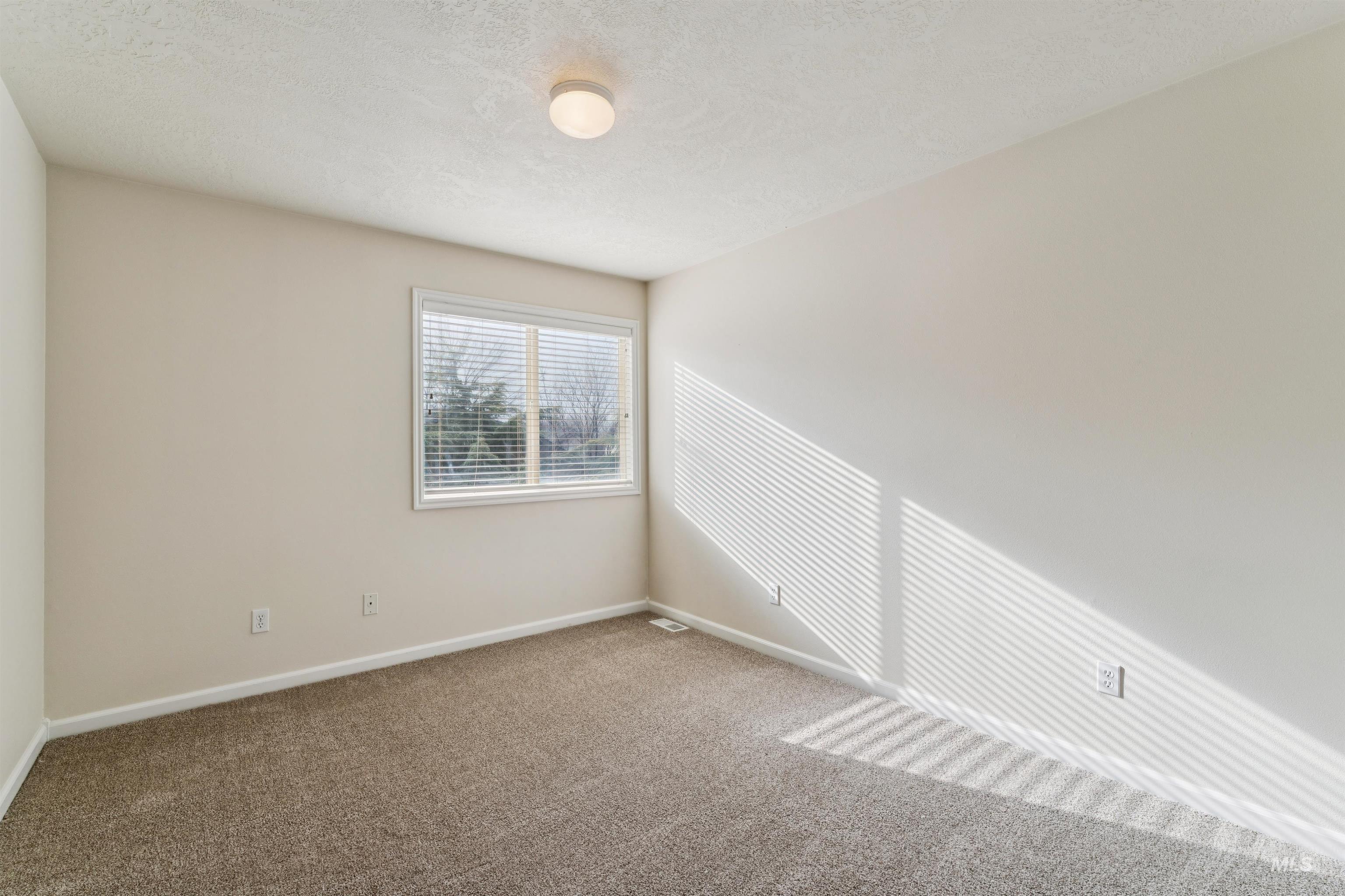 Unfurnished room with a textured ceiling and carpet flooring