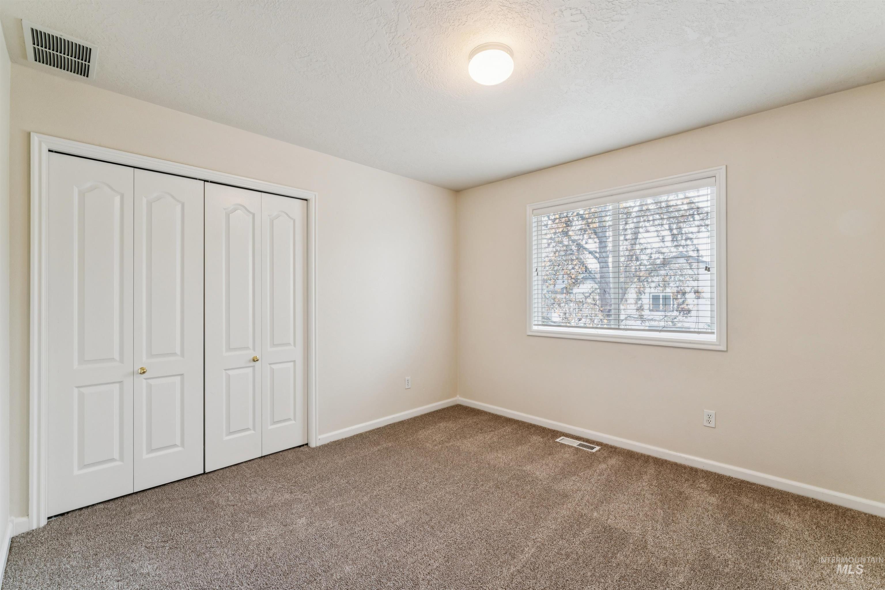 Unfurnished bedroom featuring a closet, a textured ceiling, and carpet