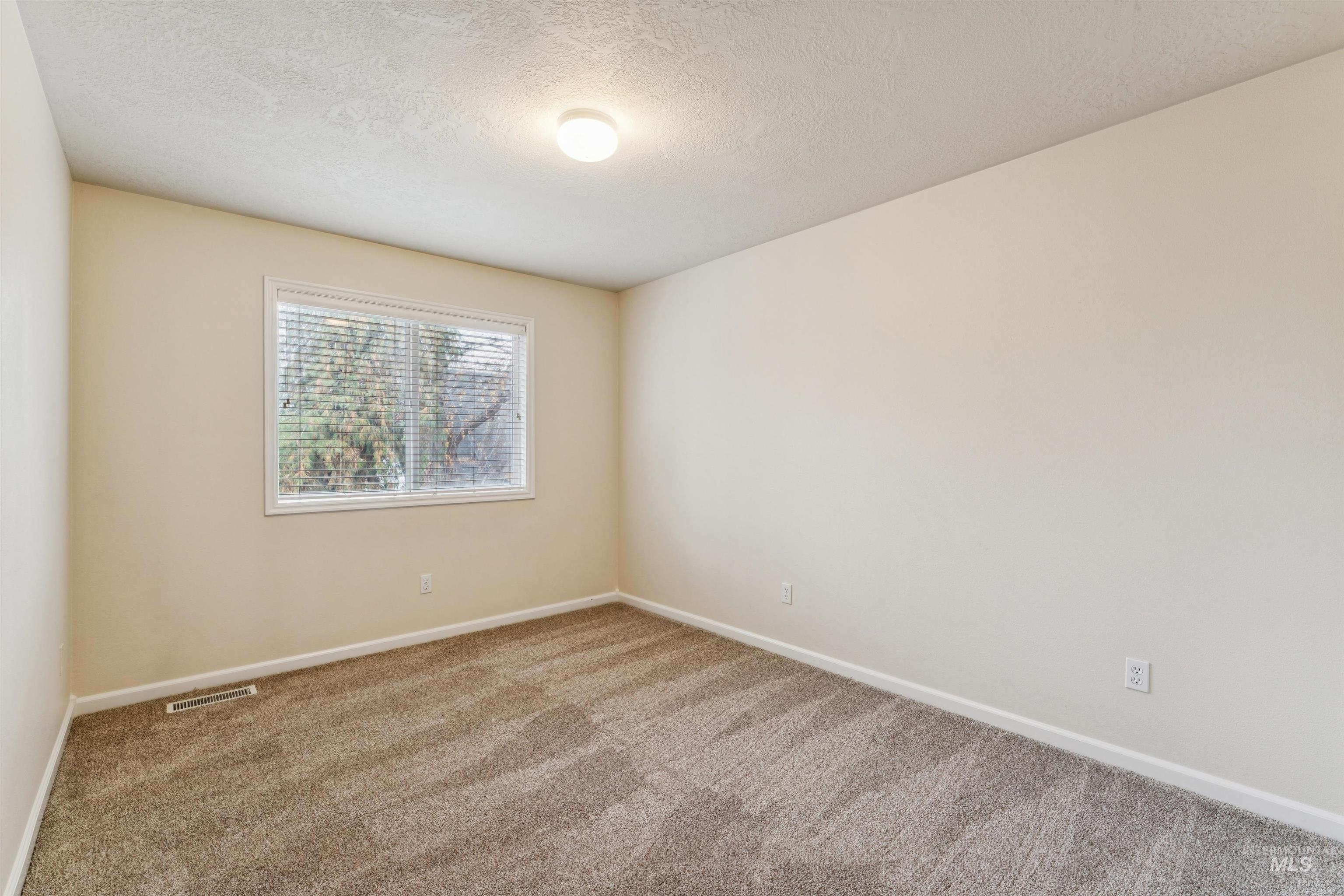 Empty room with a textured ceiling and carpet