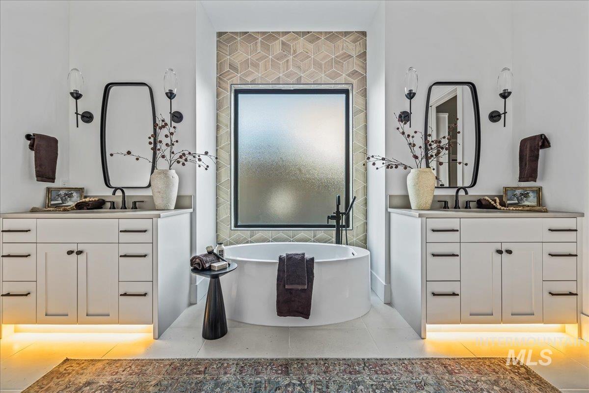 Full bath featuring two vanities, a soaking tub, and light tile patterned floors
