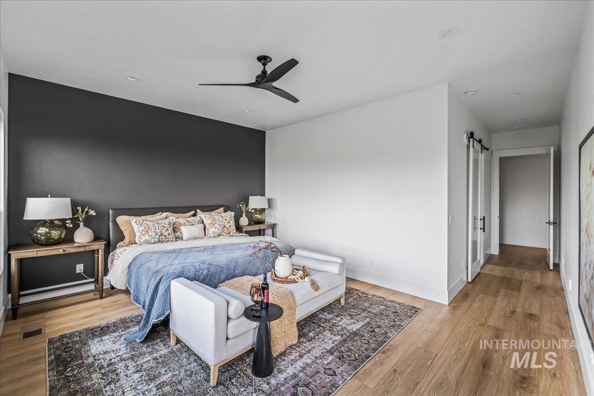 Bedroom featuring a barn door, wood finished floors, and a ceiling fan