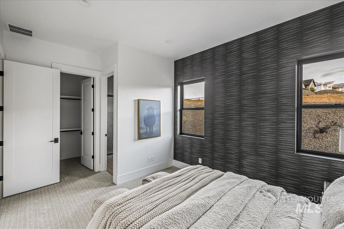 Carpeted bedroom featuring a walk in closet and baseboards
