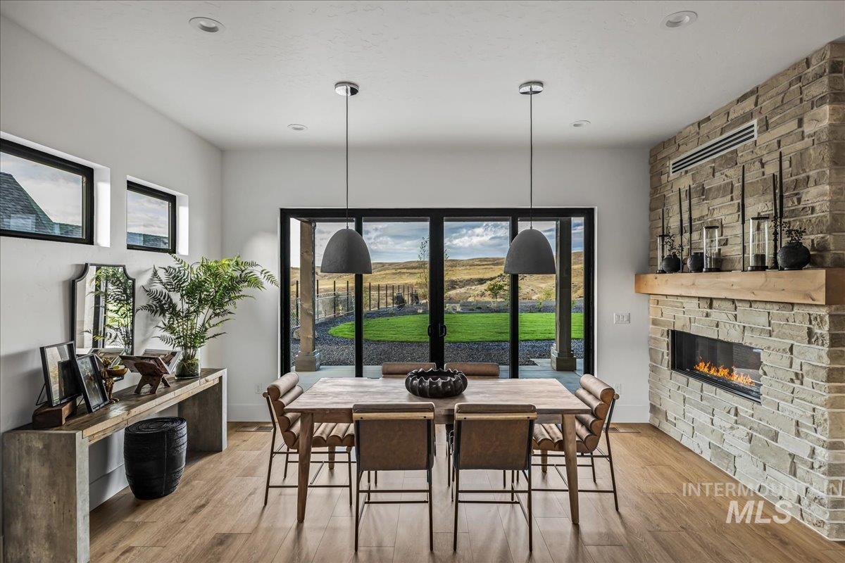 Dining room featuring wood finished floors and a stone fireplace