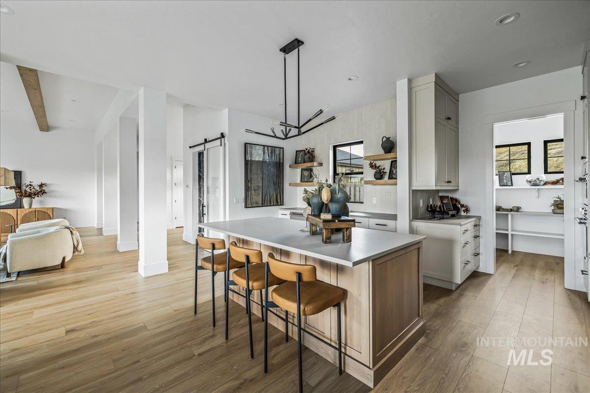 Kitchen with a barn door, hanging light fixtures, a kitchen breakfast bar, a center island, and light wood-style floors