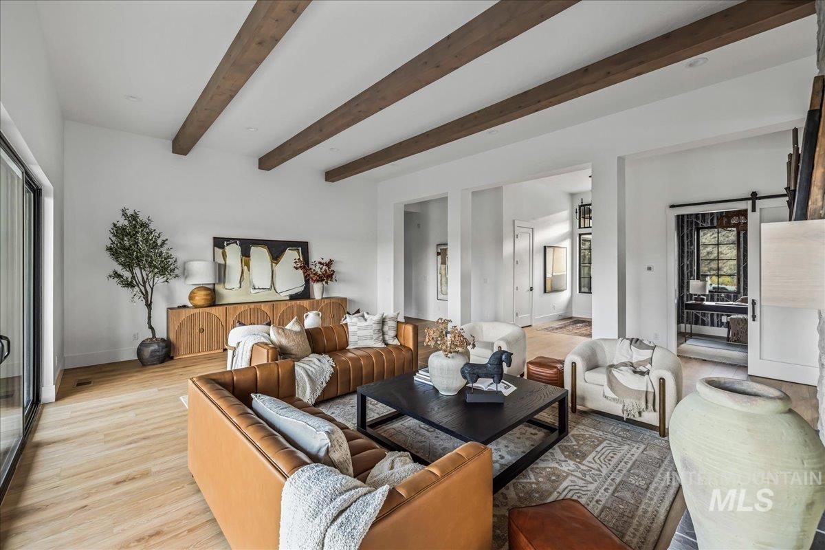 Living room with a barn door, beamed ceiling, and light wood-style flooring