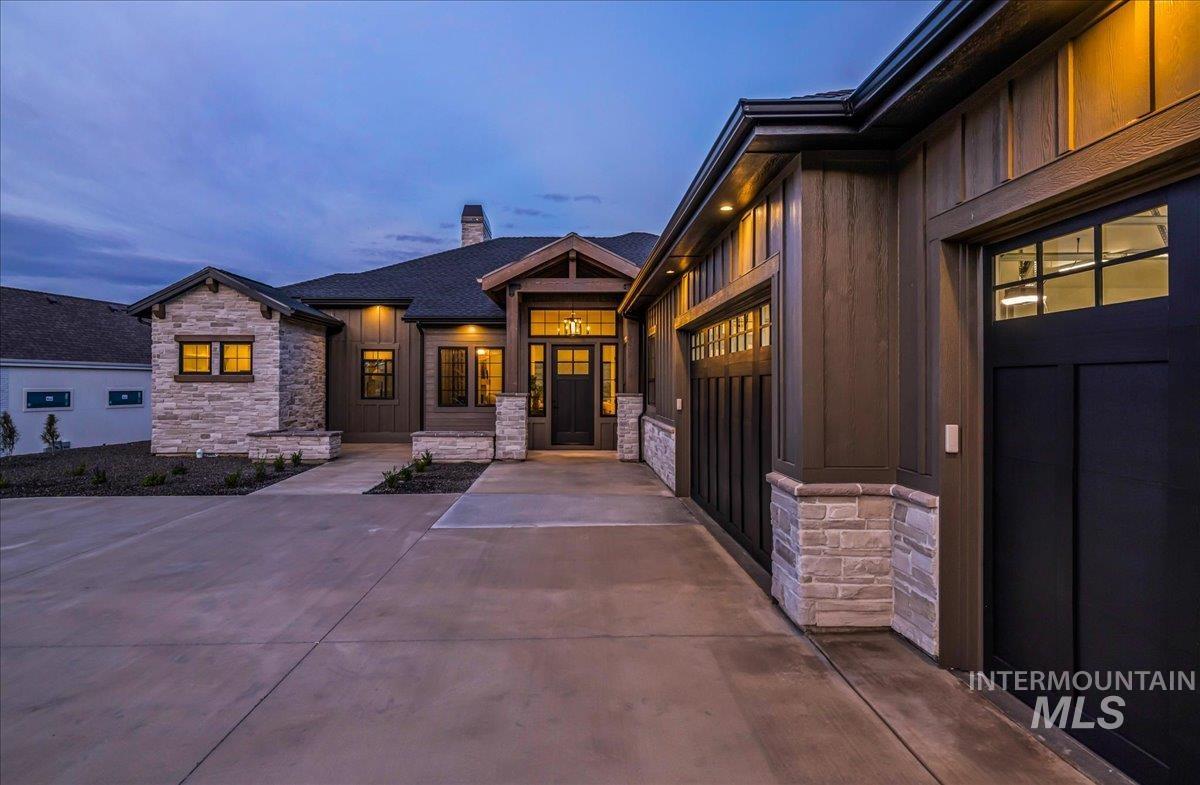 Exterior entry at dusk featuring board and batten siding, stone siding, and a chimney
