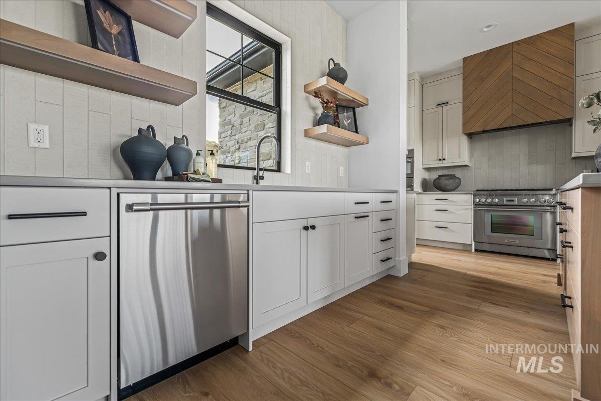 Kitchen with open shelves, white cabinetry, appliances with stainless steel finishes, and decorative backsplash