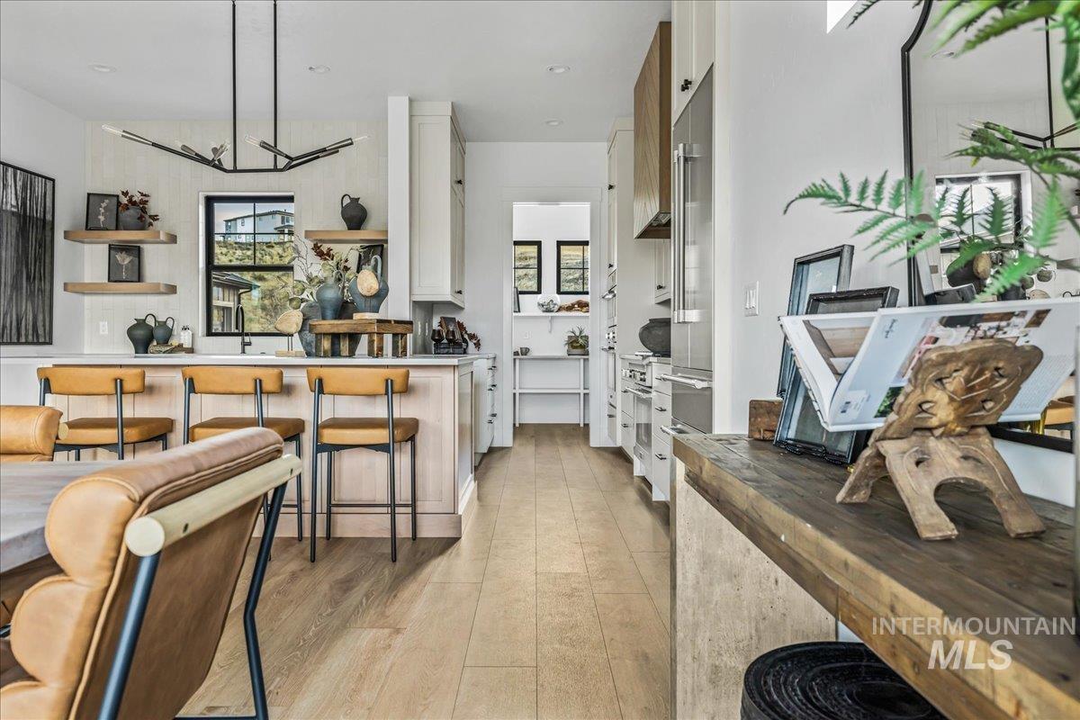 Kitchen featuring butcher block counters, white cabinetry, a breakfast bar, light wood finished floors, and pendant lighting