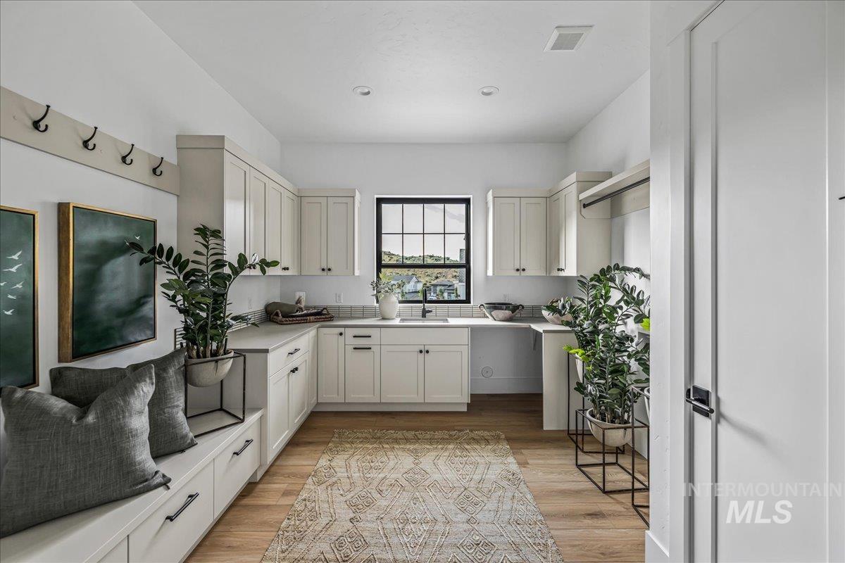 Kitchen featuring light wood finished floors, light countertops, and white cabinets