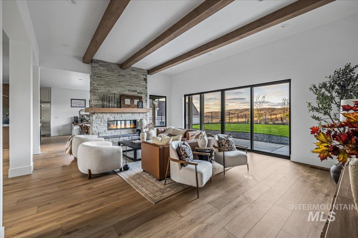 Living area with a fireplace, wood finished floors, and beamed ceiling
