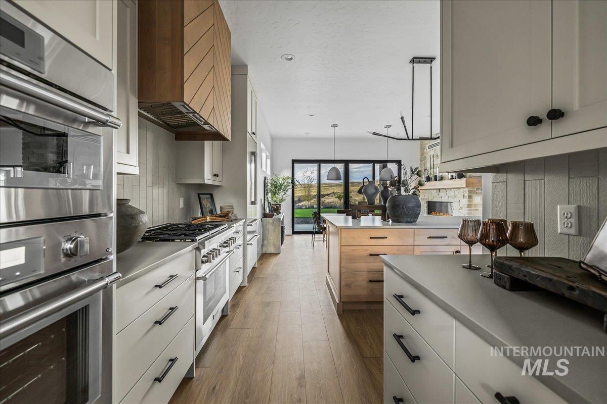 Kitchen with stainless steel appliances, light countertops, dark wood finished floors, white cabinets, and a textured ceiling