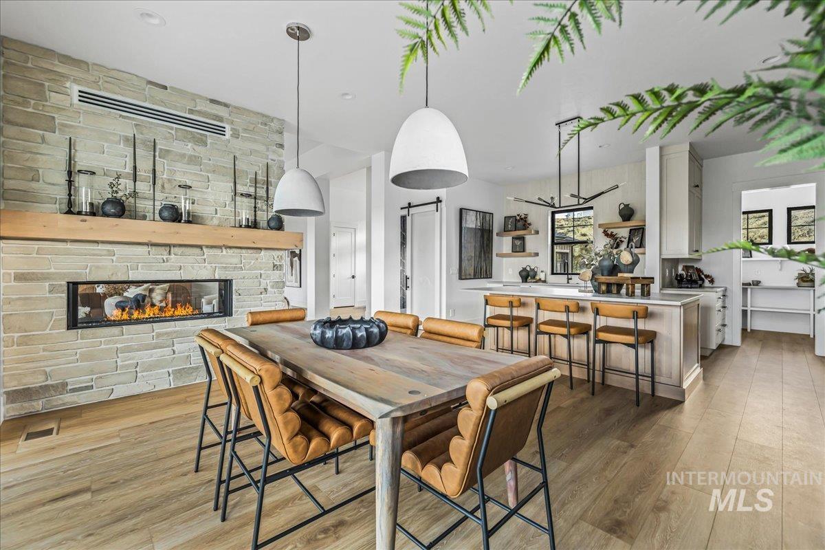 Dining space with a stone fireplace and light wood-style floors