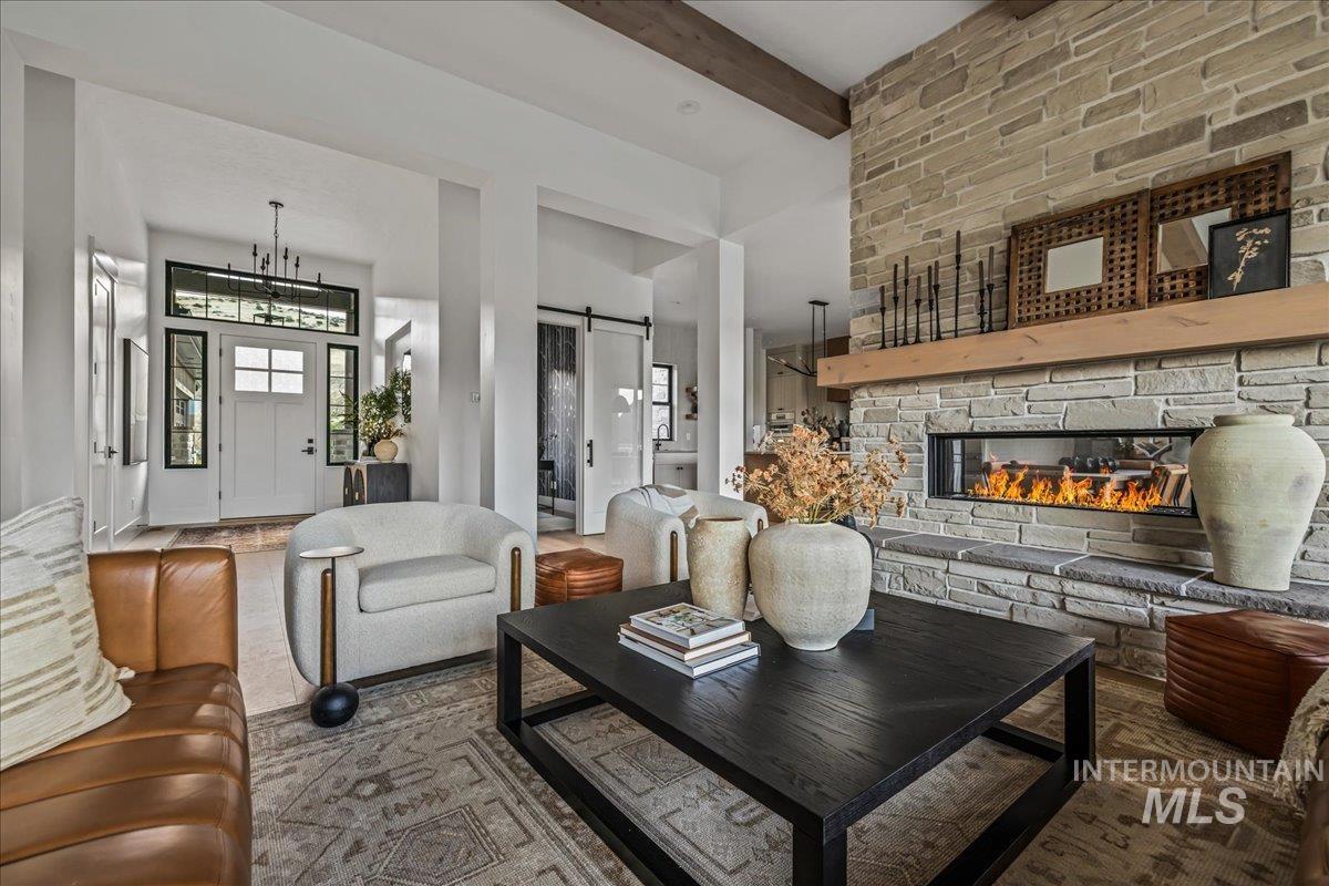 Living area featuring a barn door, a fireplace, and beam ceiling