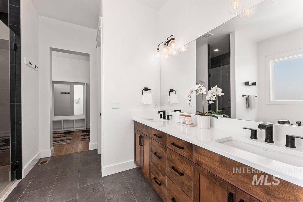 Full bath featuring double vanity and a tile shower
