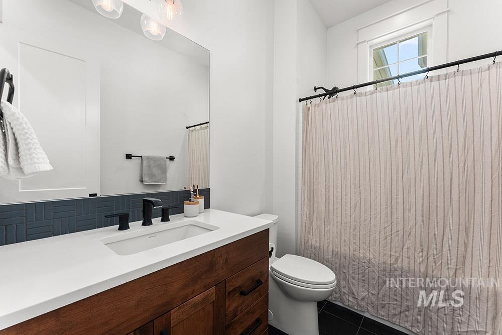 Bathroom featuring vanity, tile patterned floors, shower / bath combo with shower curtain, and tasteful backsplash