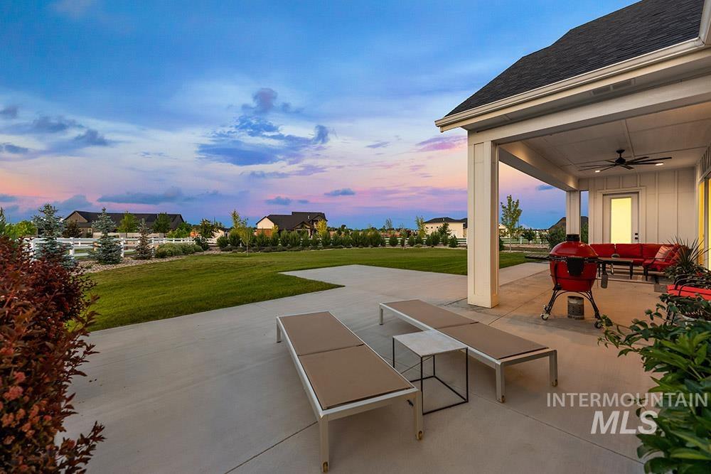 Patio terrace at dusk featuring ceiling fan, a patio area, and a yard